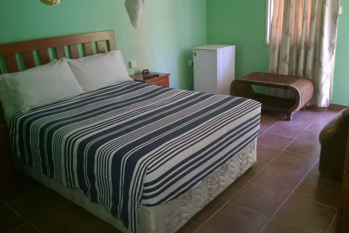 A bedroom with a bed, nightstand, and a small table.
