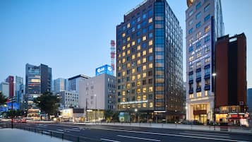 A modern hotel with a prominent glass facade, multiple floors, and illuminated signage.