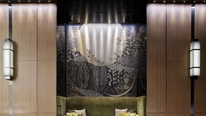 A modern hotel lobby with a green sofa, a bench, and a suitcase.