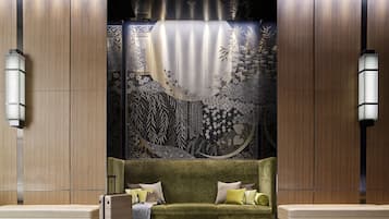 A modern hotel lobby with a green sofa, a bench, and a suitcase.