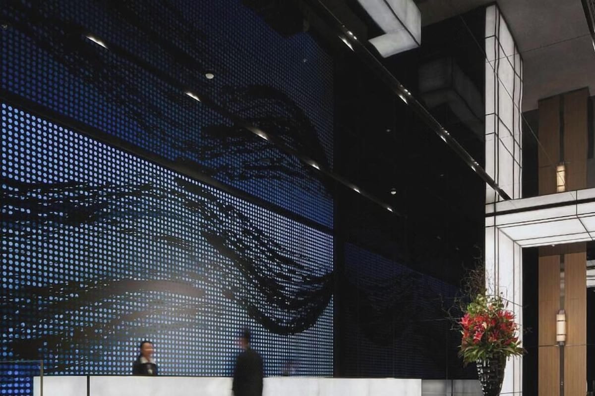 A modern lobby with a large digital display and a reception desk.