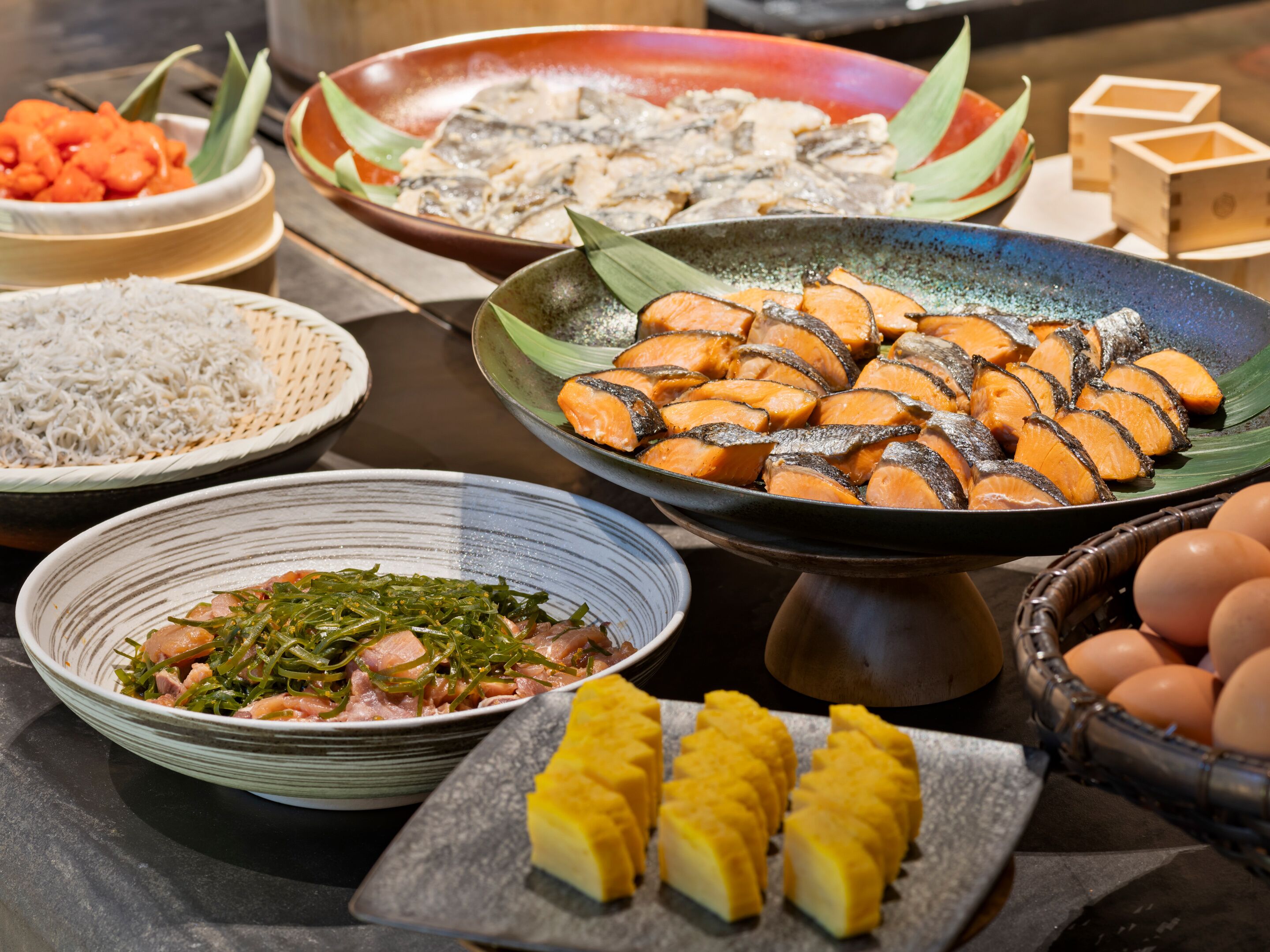 A variety of dishes including fish, rice, and vegetables on a table.