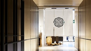 A modern hotel corridor with a wooden floor, a large decorative vase, and a geometric wall art piece. - Millennium Mitsui Garden Hotel Tokyo/Ginza (Tokyo)