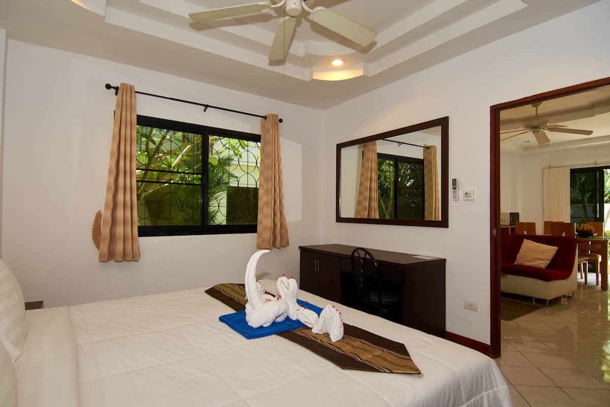 A hotel room with a bed, a desk, a chair, a mirror, and a view of the outdoors.