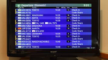 A departure board displaying domestic flight information with times, gates, and check-in instructions.
