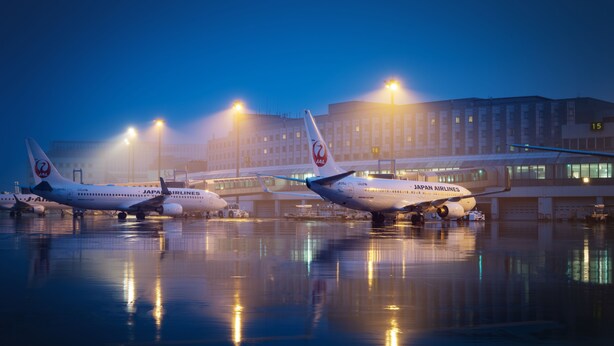 Three Japan Airlines planes parked at an airport terminal with a building in the background. - Air Terminal Hotel (Chitose)