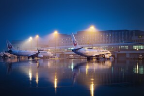 Three Japan Airlines planes parked at an airport terminal with a building in the background. - Air Terminal Hotel (Chitose)