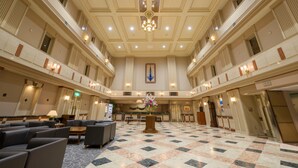 A spacious lobby with a checkered floor, multiple seating areas, and a central floral arrangement. - Air Terminal Hotel (Chitose)