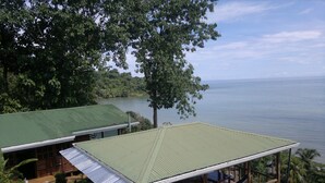 Une cabane en bois, surmontée d’un toit vert, qui surplombe un lac et est entourée d’une végétation luxuriante.