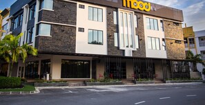 A modern hotel with a prominent 'MOO' sign, large windows, and a covered entrance area with outdoor seating. - Mood Hotel (Johor Bahru)