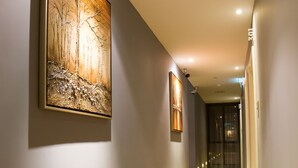 A hallway with wooden flooring, a large abstract painting on the left wall, and recessed lighting. - Mood Hotel (Johor Bahru)