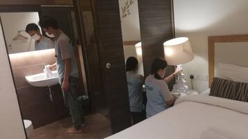 A hotel room with a bed, a bedside table with a lamp, a bathroom with a sink, and a mirror.