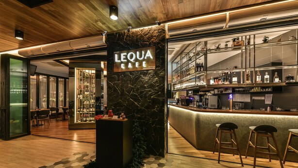 A bar area with a marble wall, wooden flooring, and a sign that reads "LEQUA CAFE". - Mood Hotel (Johor Bahru)