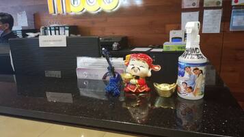 A reception desk with a 'Mood' sign, a hand sanitizer dispenser, a 'Perfect Line' face and body wash, and a decorative figurine.