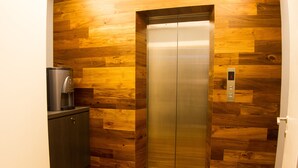 An elevator with a digital display, wooden paneling, and a coffee machine. - Mood Hotel (Johor Bahru)