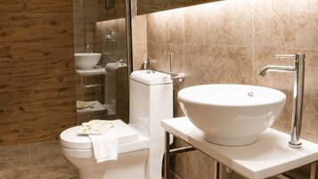 A modern bathroom with a glass-enclosed shower, a white toilet, and a sink with a mirror above it.