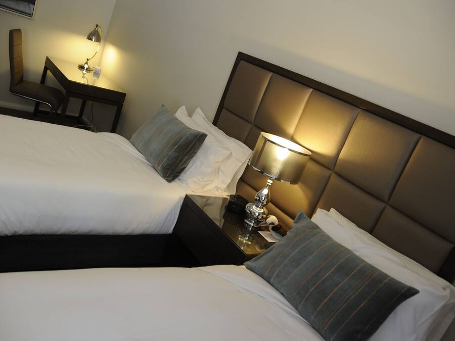 Een hotelkamer met twee bedden, een bureau en een stoel.