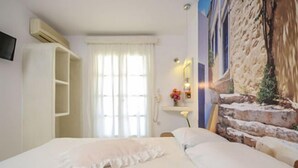 Une chambre à coucher comprenant un lit, une armoire, un miroir et un téléviseur fixé au mur.