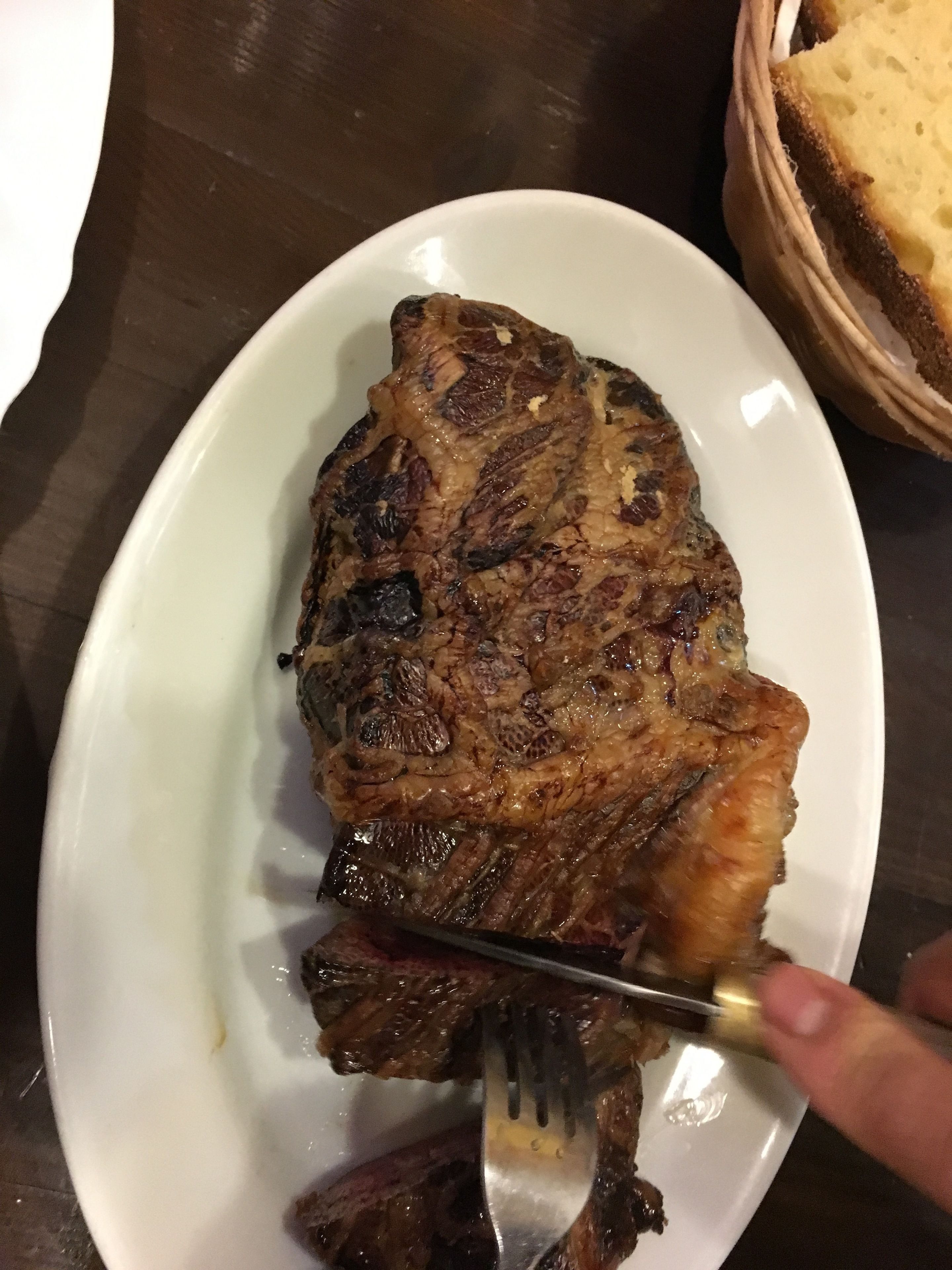 A steak on a white plate with a fork.