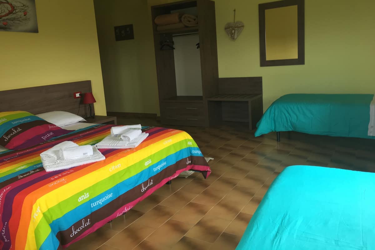 A hotel room with a bed, a desk, and a chair. There is a mirror on the wall and a window.