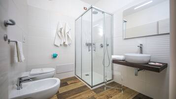 Un bany modern amb una dutxa tancada amb vidre, un lavabo blanc i un vàter.