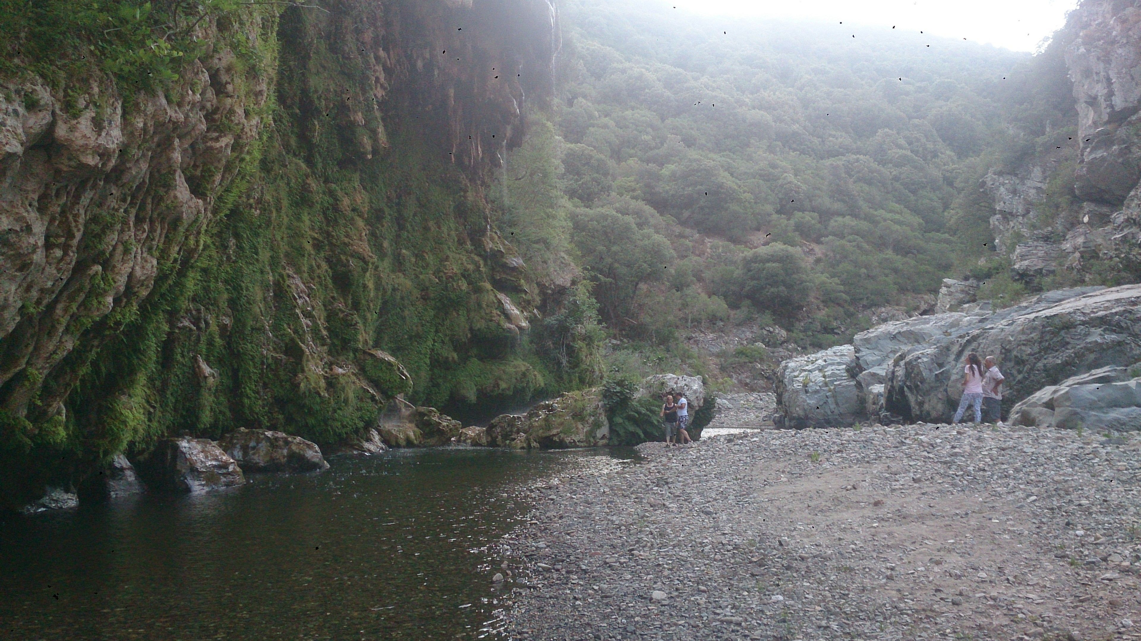 Un letto di fiume roccioso con un gruppo di persone in riva all'acqua.