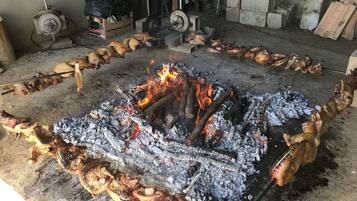 Un fogón tradicional al aire libre, rodeado de brochetas de carne.