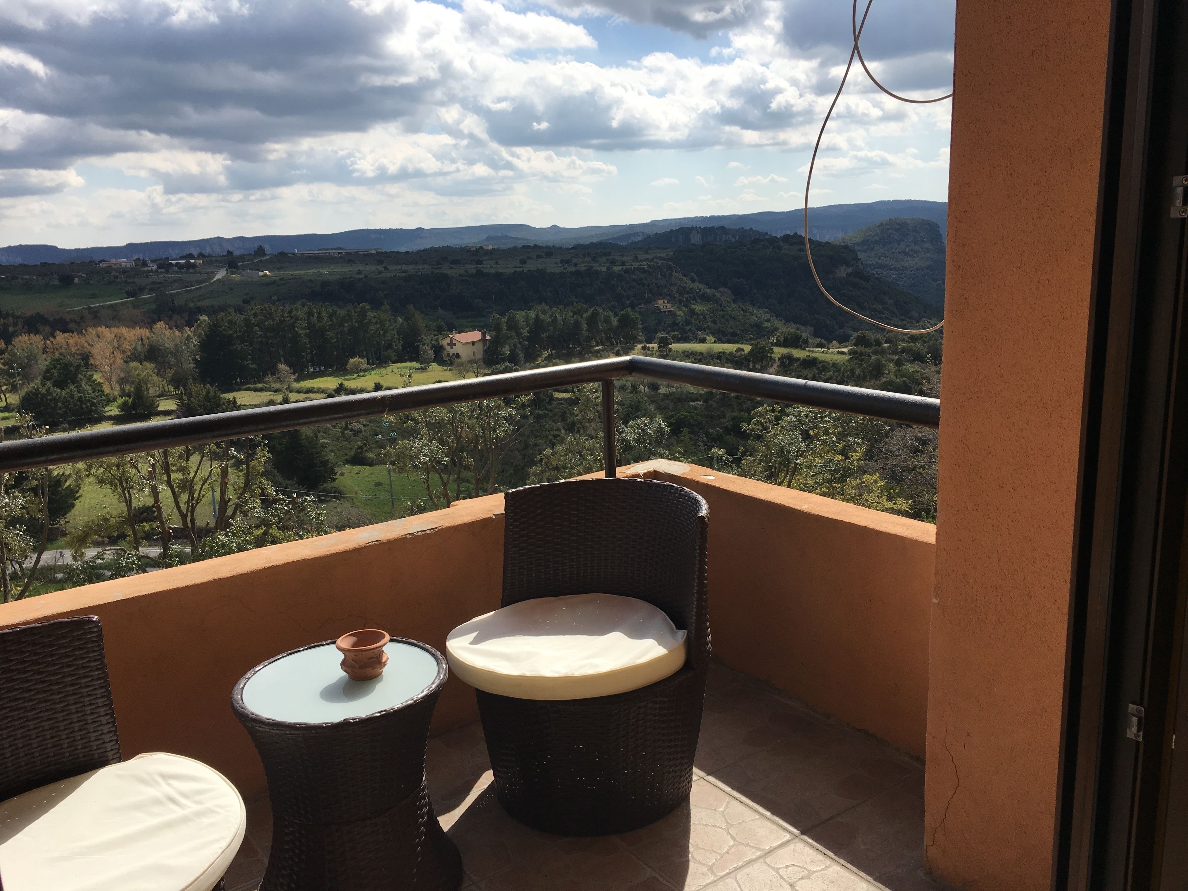 Ein Balkon mit Korbmöbeln und Blick auf eine grüne Landschaft.