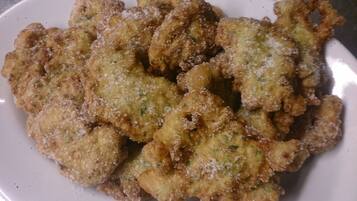 Een bord met gefrituurde snacks, vermoedelijk bollen, met een goudbruine korst en bestrooid met een witte kruiding, mogelijk zout of suiker.