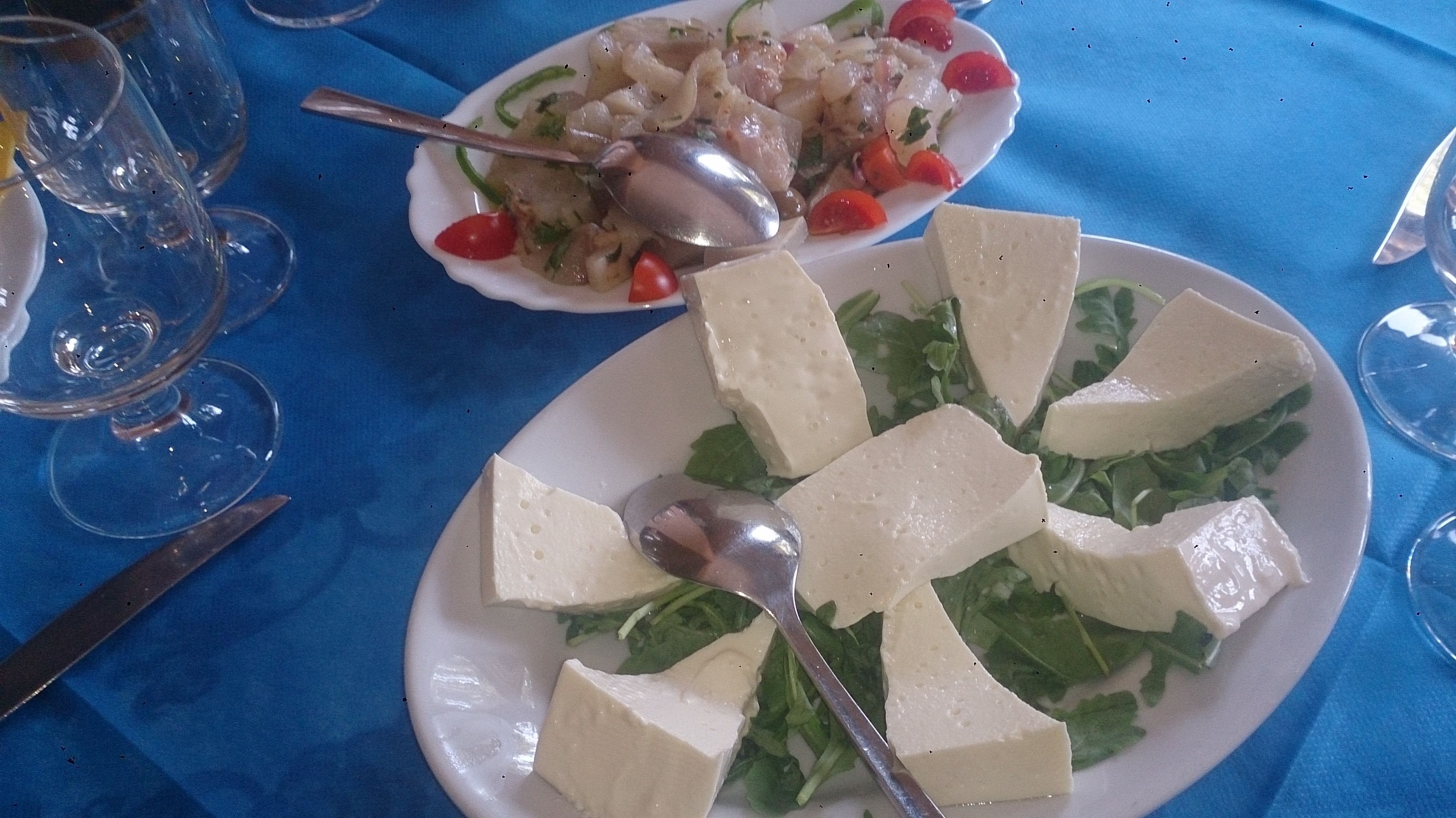 Ein Esstisch mit Tellern voller Essen, einem Löffel und Weingläsern.