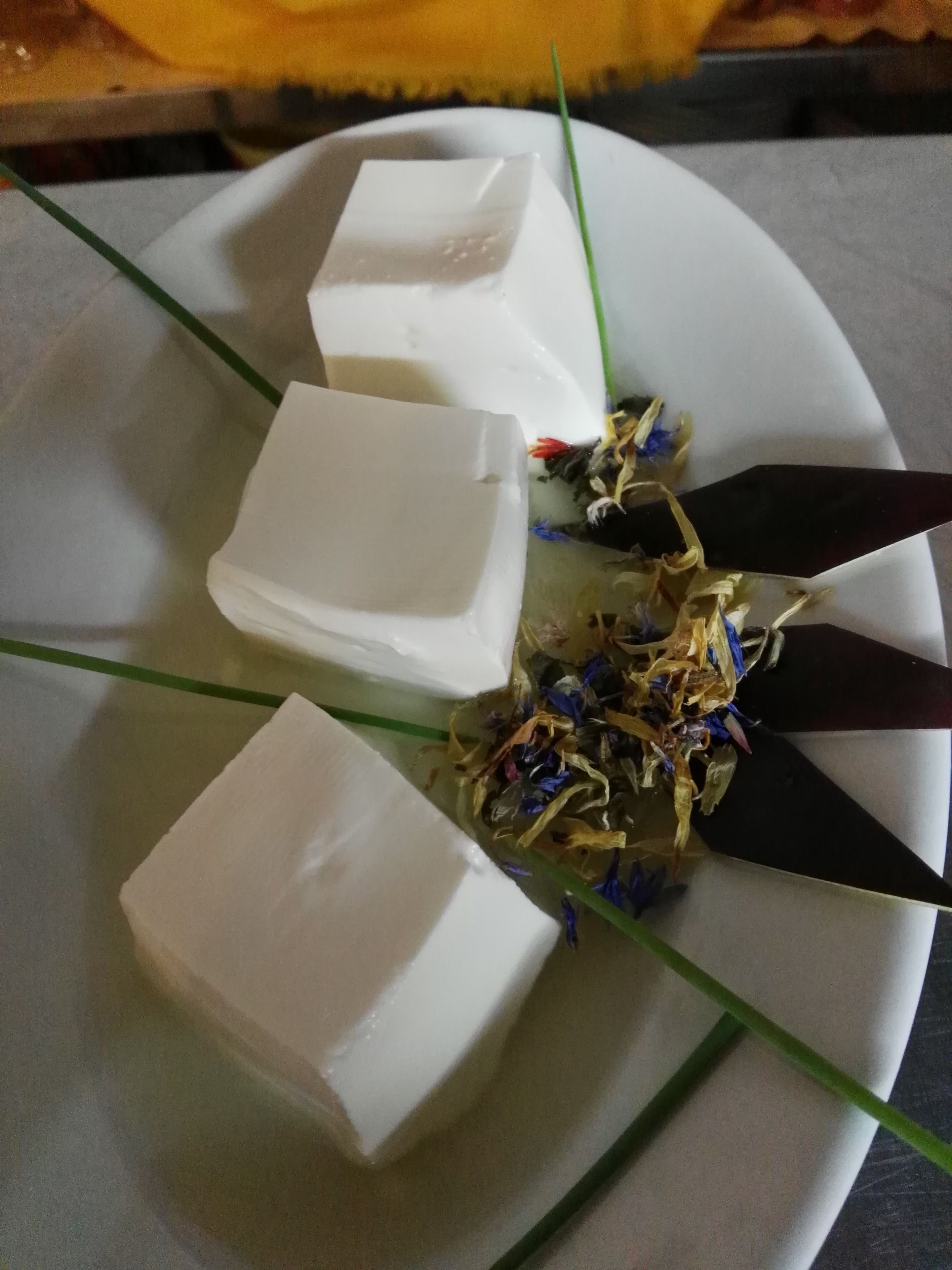 A white plate with three white cubes and a black knife with a green handle.