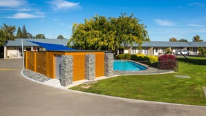 A hotel with a swimming pool, a covered outdoor area, and a well-maintained lawn. - Cherylea Motel (Blenheim)