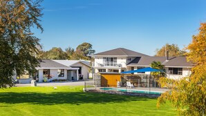 A residential building with a swimming pool, a covered patio, and a well-maintained lawn. - Cherylea Motel (Blenheim)