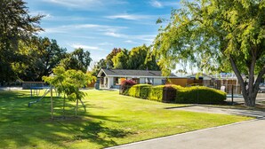 A residential area with a house, a well-maintained lawn, and a playground. - Cherylea Motel (Blenheim)