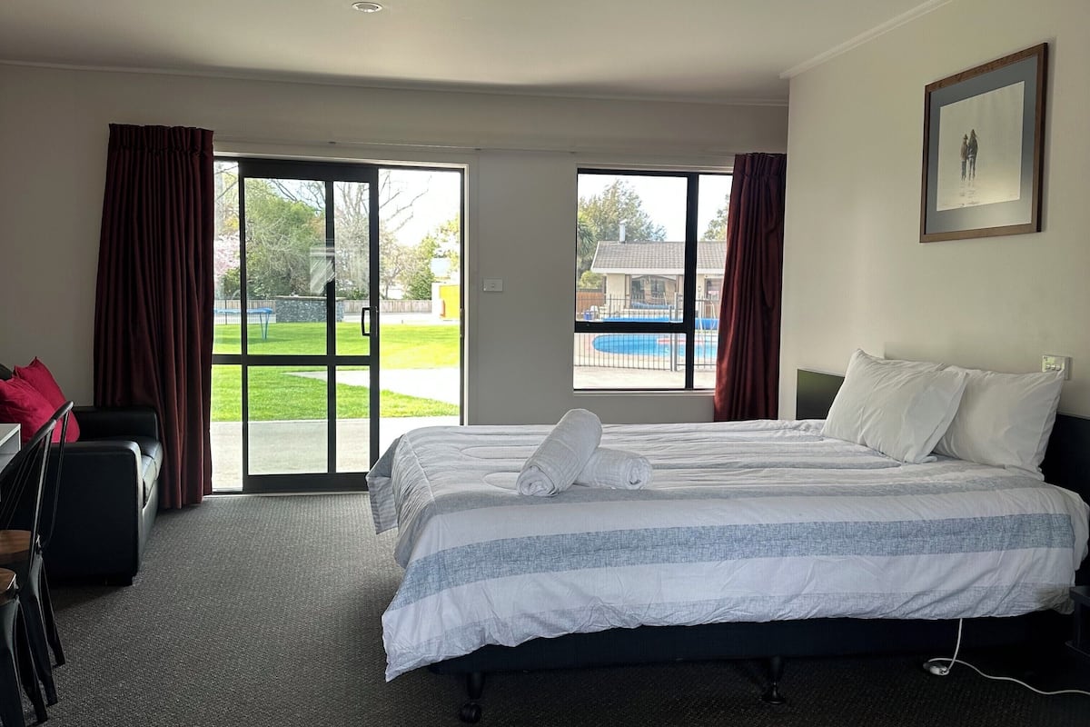 A hotel room with two beds, a desk, and a view of a swimming pool.