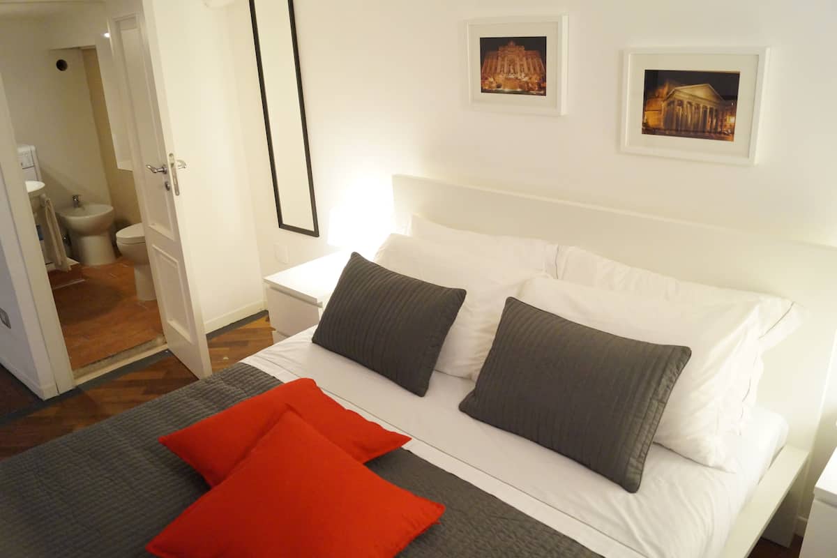 Ein Hotelzimmer mit einem Bett, zwei Kissen, einem Nachttisch und einer Wand mit gerahmten Bildern.