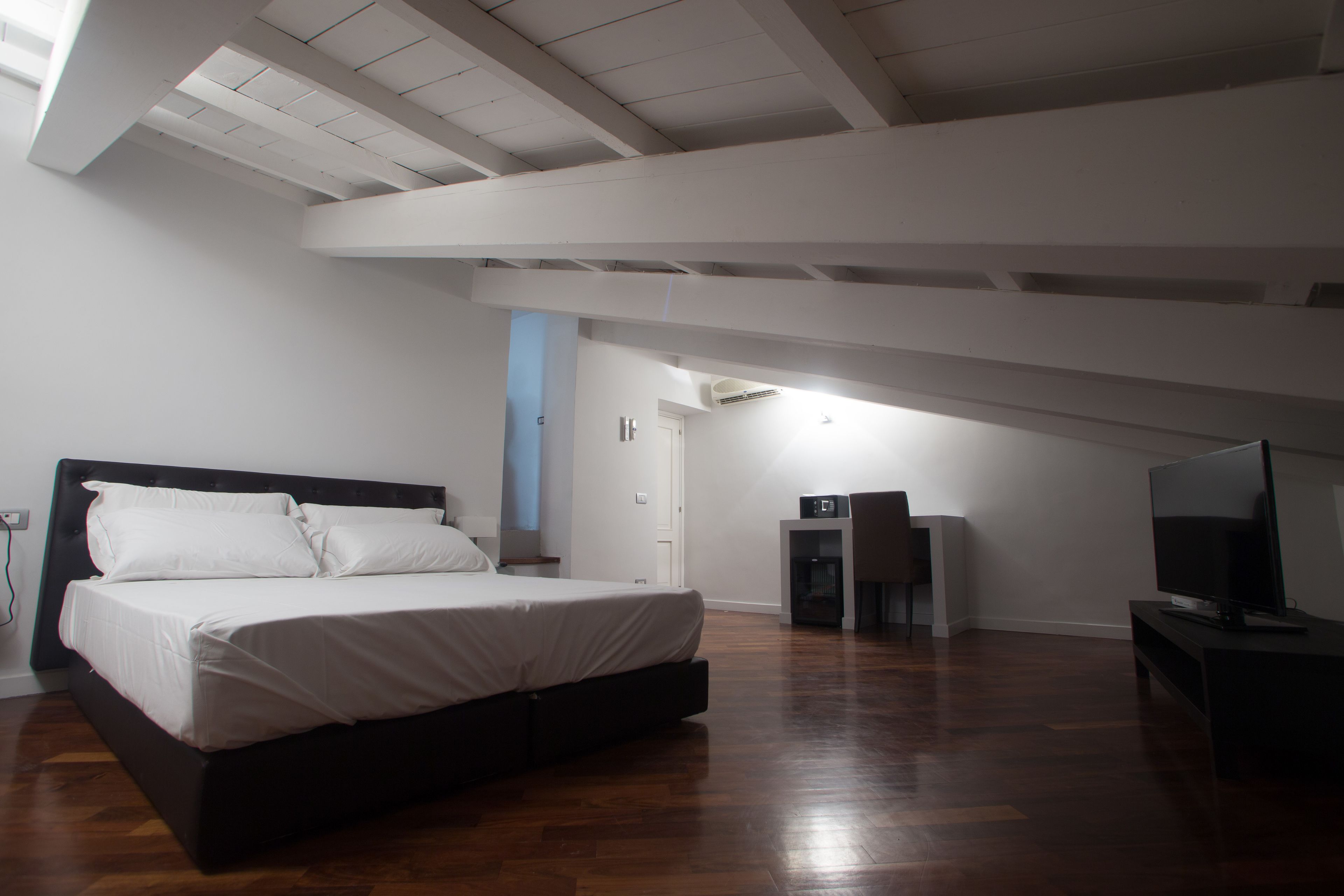 A bedroom with a bed, a television, and a small table.