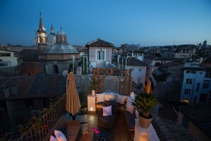 A rooftop terrace with outdoor seating, a view of the cityscape, and a church in the background. - Relais Arco della Pace (Rome)