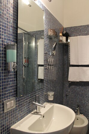 Un bagno con uno specchio grande, un lavandino, un bidet e pareti rivestite di piastrelle blu.