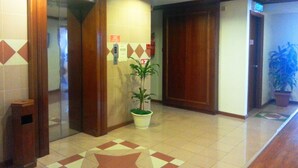 A hotel lobby with a tiled floor, wooden doors, and a potted plant. - Sanbay Hotel (Sandakan)