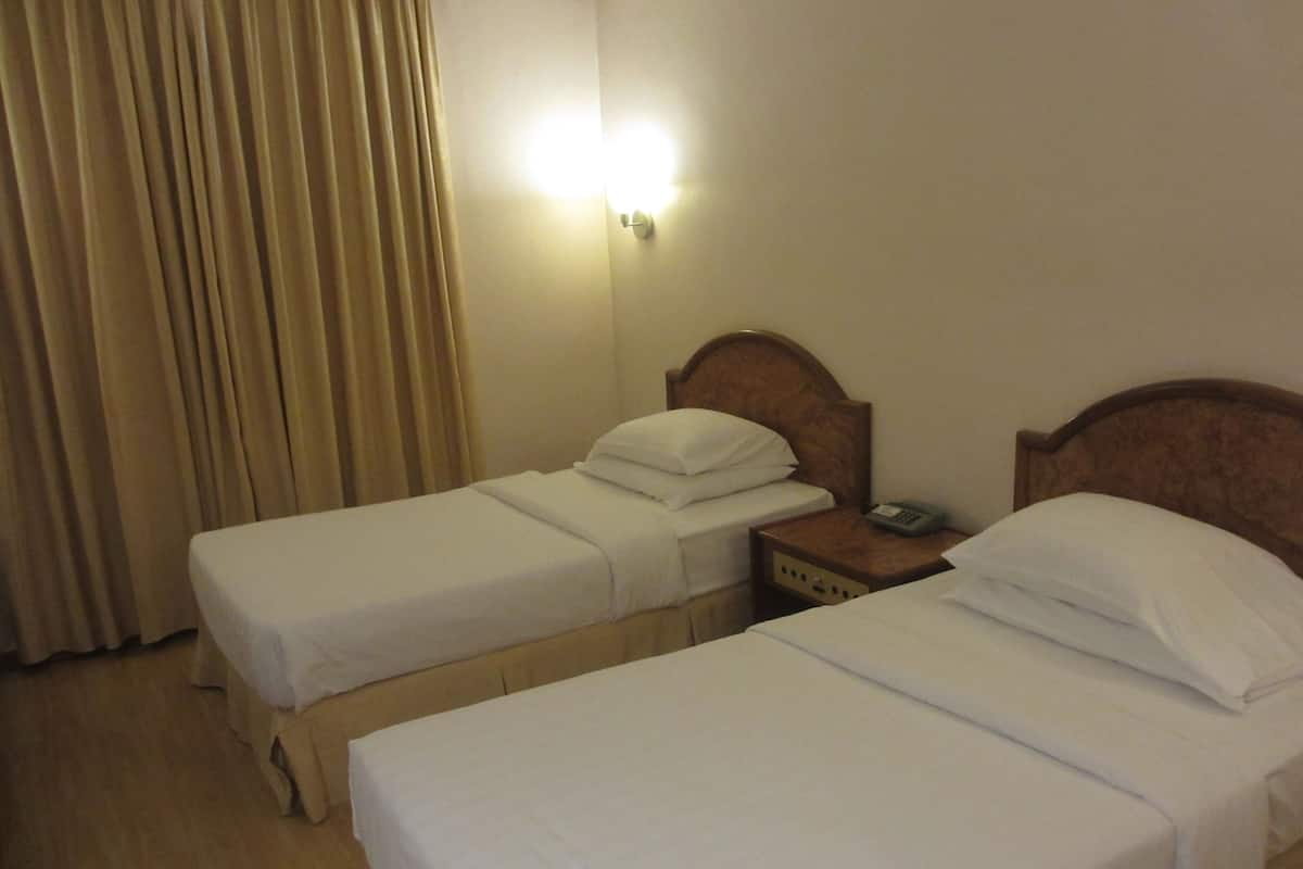 Ein Hotelzimmer mit zwei Einzelbetten, einem Nachttisch mit Telefon und einer Wandlampe.