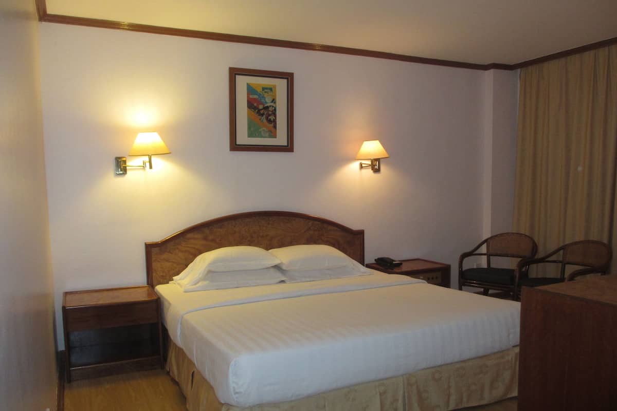 Ein Hotelzimmer mit einem großen Bett, zwei Nachttischlampen, einem Nachttisch, einem Sessel und einem Bild an der Wand.