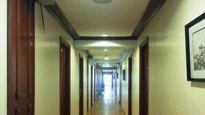 A long, narrow hallway with wooden floors and doors on both sides, leading to a bright exit at the end. - Sanbay Hotel (Sandakan)