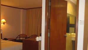 A hotel room with a bed, a desk, a chair, a lamp, and a bathroom visible through an open door. - Sanbay Hotel (Sandakan)