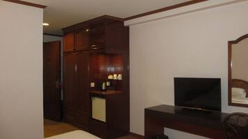 A hotel room with a bed, a TV, a desk, a mirror, and a wardrobe.