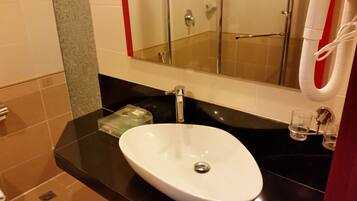 A bathroom with a white sink, a mirror, and a glass shower enclosure.