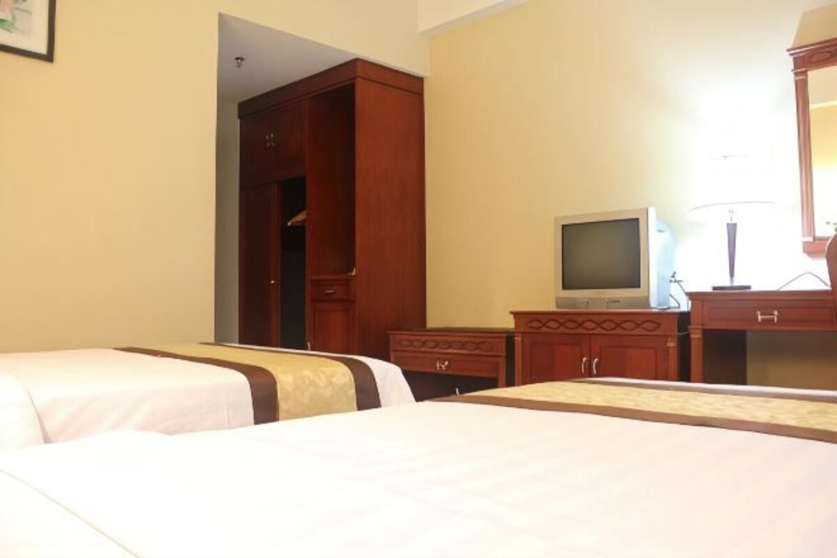 A hotel room with two beds, a television, a desk, and a wardrobe.