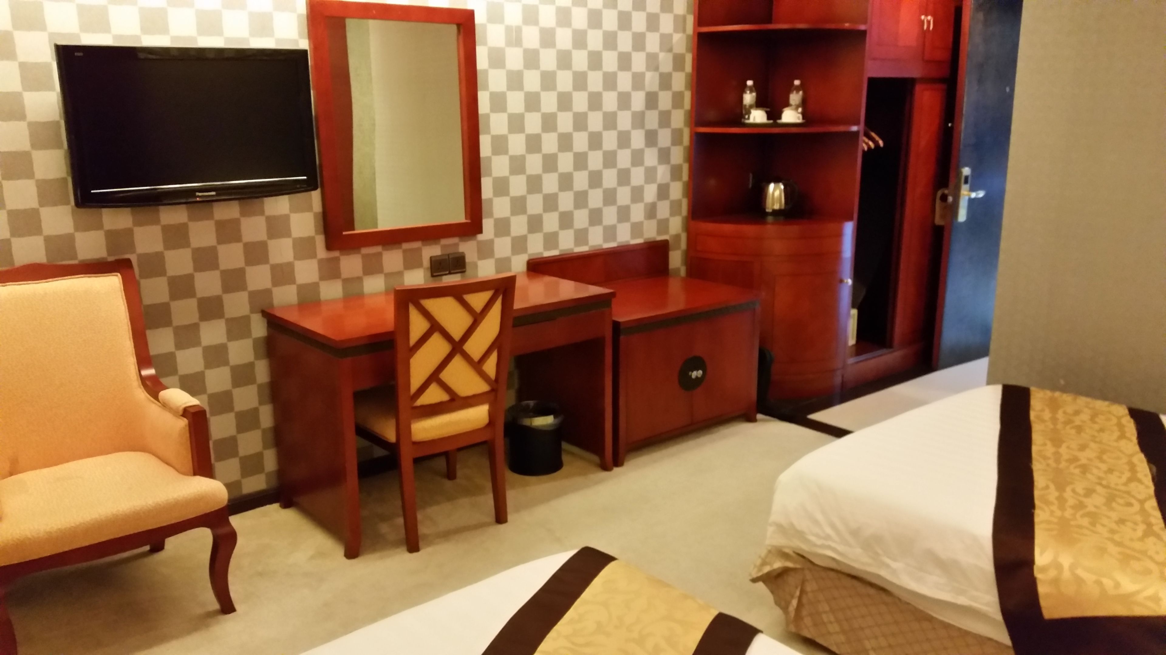 A hotel room with a bed, a desk, a chair, a television, and a wardrobe.