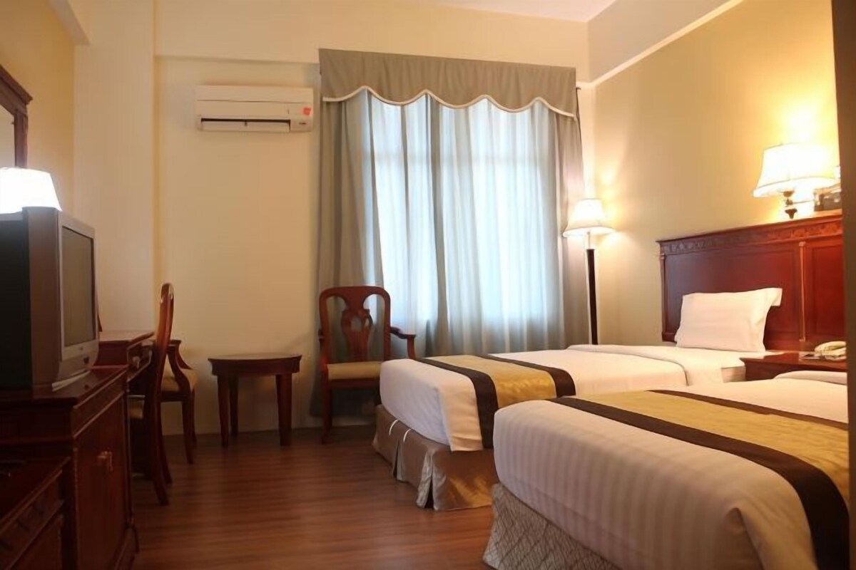 A hotel room with two beds, a desk, a chair, and a television.