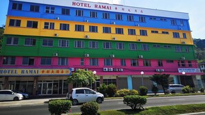 Un hôtel à plusieurs étages, doté d’une façade aux couleurs vives, sur laquelle on peut lire l’inscription « HÔTEL RAMAI ».